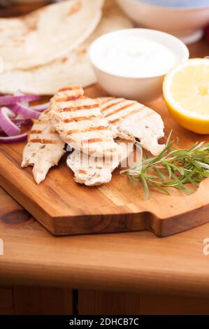 Huhn pita Wrap mit Tomate, Kartoffel und Tzatziki und einem seitlichen Griechischer Salat Stockfoto