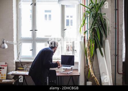 Geschäftsmann mit Laptop am Schreibtisch im Kreativbüro Stockfoto
