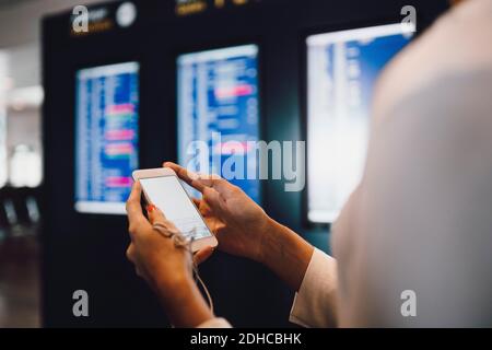 Mittelteil einer Geschäftsfrau, die am Flughafen telefoniert Stockfoto