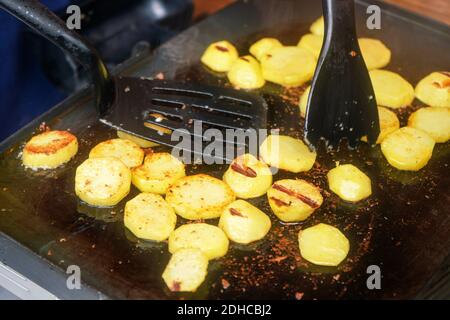 Kartoffeln in kleine Kreise geschnitten, gewürzt mit Gewürzen, gegrillt auf elektrischem Grill Stockfoto