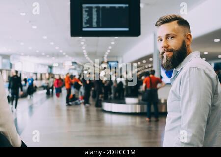 Porträt eines lächelnden Geschäftsmannes, der mit einer Geschäftsfrau am Flughafen steht Stockfoto