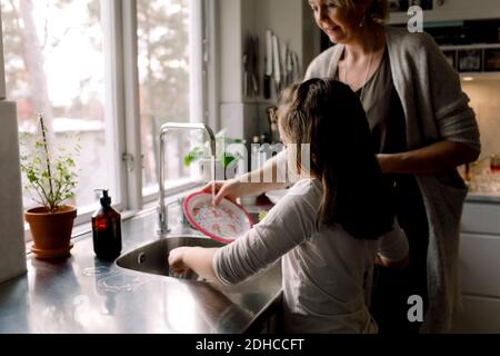 Tochter helfende Mutter in der Küche zu Hause Stockfoto