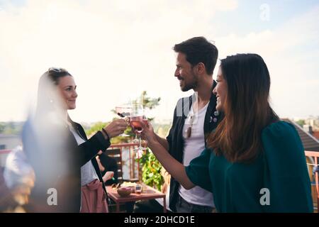 Lächelnde Freunde, die Getränke beim Feiern auf der Terrasse genießen Stockfoto