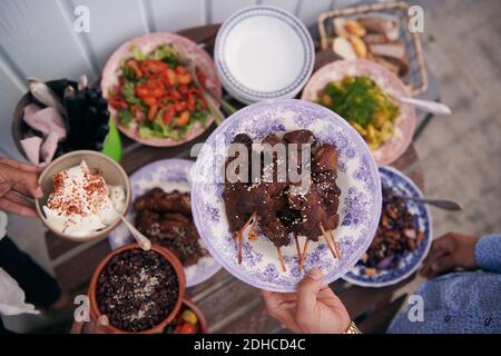 Man hat einen Blick auf die Hand des Mannes, der gekochtes Fleisch hält Buffet während der Party Stockfoto