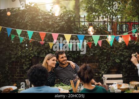 Lächelnde männliche und weibliche Freunde posieren für Foto während des Abendessens Party im Hinterhof Stockfoto