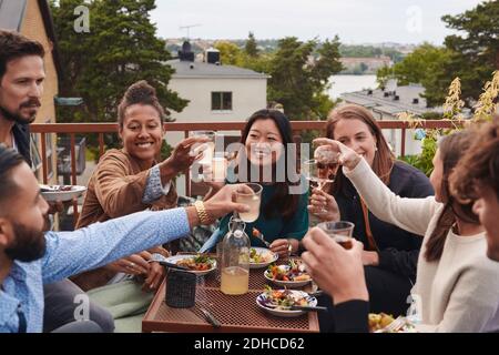 Fröhliche Freunde, die auf der Terrasse sitzen und Getränke genießen Stockfoto