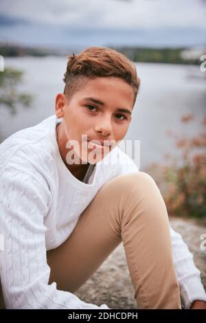 Porträt eines selbstbewussten Jungen im Teenageralter, der am Seeufer im Park sitzt Während des Picknicks Stockfoto