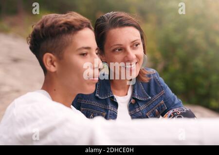 Mutter und Sohn blicken weg, während sie im Park sitzen Stockfoto