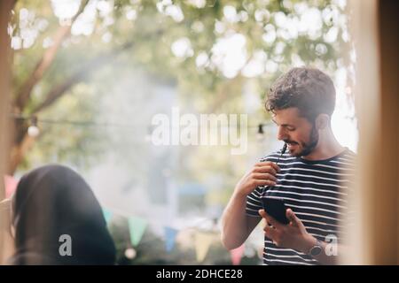 Junger Mann, der durch Kopfhörer spricht, während er auf dem Balkon steht Party Stockfoto
