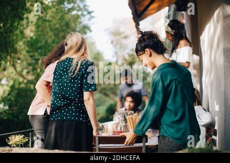 Multiethnische männliche und weibliche Freunde am Tisch im Balkon während Party Stockfoto