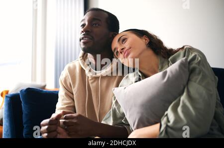 Liebevolle junge gemischte Ethnizität Paar kuscheln, während auf dem Sofa sitzen Zu Hause, um gemeinsam romantische Filme im fernsehen zu sehen oder zu streamen Stockfoto