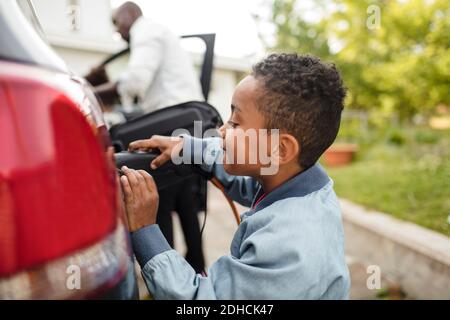 Seitenansicht des Jungen beim Laden des Elektroautos Stockfoto
