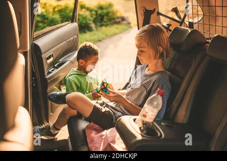 Mädchen spielen Puzzle-Würfel, während im Auto von Bruder sitzen Im Park Stockfoto