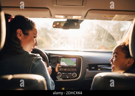 Lächelnde Frau mit Tochter, die während des Picknicks im Elektroauto sitzt Stockfoto