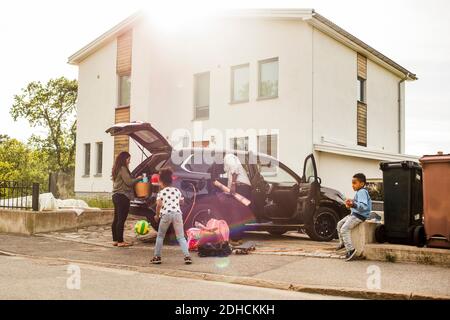 Familie mit Elektroauto auf Auffahrt gegen Haus Stockfoto