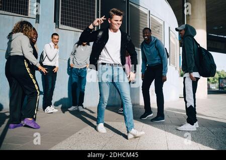 Fröhliche Freunde, die jungen Mann auf dem Bürgersteig in Stadt Stockfoto