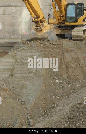 Eine Vertikale einer gelben Arbeitsbaghoe auf einem Stapel Von Schmutz auf einer Baustelle Stockfoto