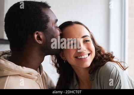 Liebevolle junge gemischte Ethnizität Paar kuscheln und küssen während des Stehens In der Küche zusammen Stockfoto