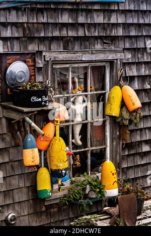 Bojen schmücken die Seite einer Fischhütte an einem nebligen Morgen im malerischen Fischerhafen von Port Clyde, Maine. Stockfoto