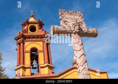 Die Parroquia San Sebastian Kirche mit dekorativem Kreuz und Glockenturm im schönen Kolonialdorf Bernal, Queretaro, Mexiko. Bernal ist eine malerische Kolonialstadt bekannt für die Pena de Bernal, ein riesiger Monolith, der das kleine Dorf dominiert ist die dritthöchste auf dem Planeten. Stockfoto