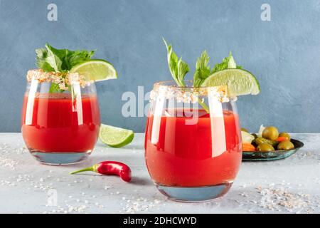 Bloody Mary Cocktails mit Gurken und einem roten Paprika, garniert mit Limette und Sellerie Stockfoto