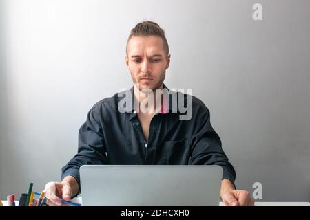 Serious Kaukasischen Mann arbeitet in seinem Laptop, in Quarantäne für die Coronavirus-Pandemie Stockfoto
