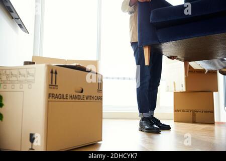 Nahaufnahme des Menschen am Umzug in neue Heimat Sofa in der Lounge, umgeben von Umzugskartons Stockfoto