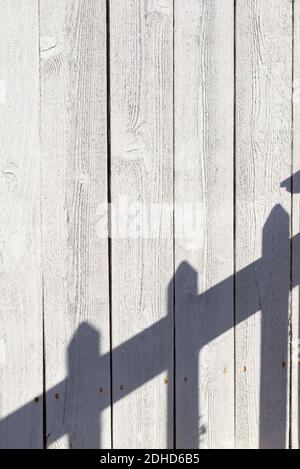 Ein Zaun wirft einen Schatten auf einen anderen Zaun. Stockfoto