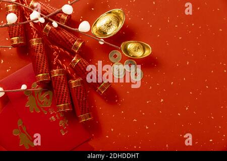 Eine Draufsicht von roten Geschenkumschlägen, Feuerwerkskörpern, Goldbarren und Kupfermünzen auf dem roten Hintergrund mit weißen Flecken, einem chinesischen Neujahrsthema Stockfoto