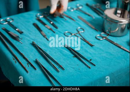 Chirurg Hand tragen medizinische Handschuhe Auswahl chirurgische Instrumente auf einem Tisch im Operationssaal Stockfoto