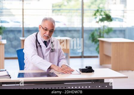 Alter männlicher Arzt, der sich in der Klinik Notizen gemacht hat Stockfoto