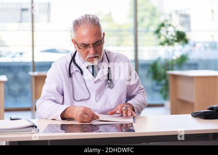 Alter männlicher Arzt, der sich in der Klinik Notizen gemacht hat Stockfoto