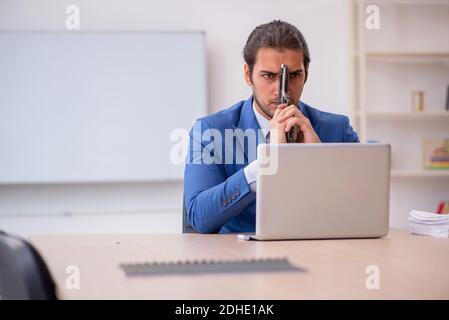 Junger männlicher Angestellter sitzt im Büro vor Whiteboard Stockfoto