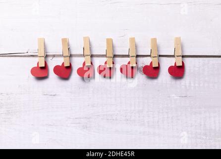 Eine Closeup aus roten Herzen mit Wäscheklammern auf der Rückseite hängen an der Wäscheleine, das Konzept der Romantik, Liebe, und St. Valentinstag Stockfoto