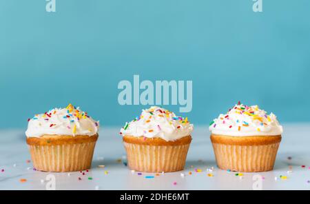 Cupcakes mit Streuseln auf weißem Tisch mit blauem Hintergrund. Stockfoto