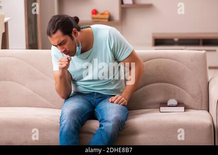 Junger Mann hustet zu Hause während einer Pandemie Stockfoto