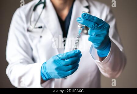 Arzt im weißen Mantel Zeichnung Impfstoff in eine Spritze für die Injektion. Stockfoto