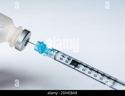 Nahaufnahme der Nadel, die den Impfstoff in die Spritze auf weißem Hintergrund zieht. Stockfoto