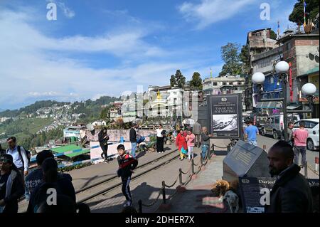 Besucher, die die Sehenswürdigkeiten von Darjeeling am Bahnhof bewundern, mit Kanchenjunga und den schneebedeckten Himalaya-Ranges, die über der Stadt emporragen Stockfoto