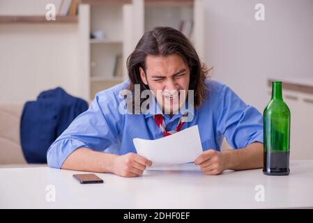 Junger männlicher Angestellter, der von seiner Arbeit zu Hause entlassen wurde Stockfoto