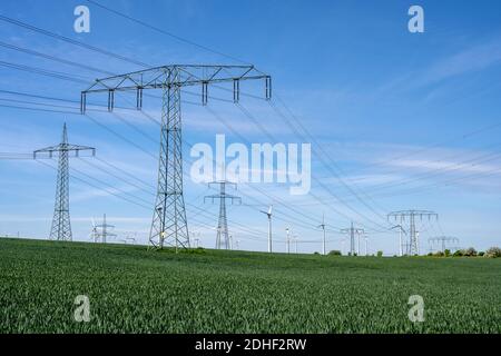 Stromleitungen mit Windturbinen im Hintergrund, in gesehen Deutschland Stockfoto