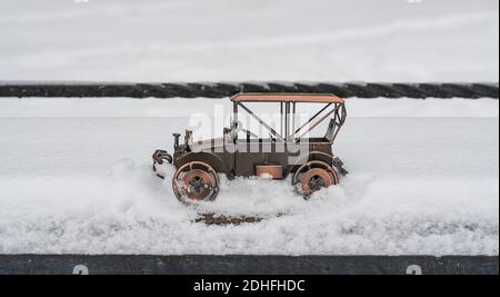 Spielzeug, Modell eines Retro-Autos steht auf der Straße im tiefen Schnee Stockfoto