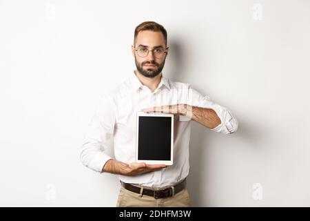 Selbstbewusster bärtiger Mann zeigt digitalen Tablet-Bildschirm, demonstriert App, stand über weißem Hintergrund Stockfoto