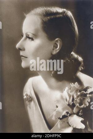 1926 , USA : GRETA GARBO in FLEISCH UND DER TEUFEL ( 1927 - La carne e il diavolo ) von Clarence Brown , aus der Romanze "die Unsterbliche Vergangenheit" von Hermann Sudermann , Kostümkleid von ADRIAN - MGM - Metro Goldwyn Mayer - FILM - HOLLYWOOD - KINO - FILM - Schauspielerin - Kleidung - weiß Satin - Raso bianco - Blume - fiore - orchidea - Orchidee - Scollatura - Ausschnitt - Halsöffnung - profilo - Profil ---- Archivio GBB Stockfoto