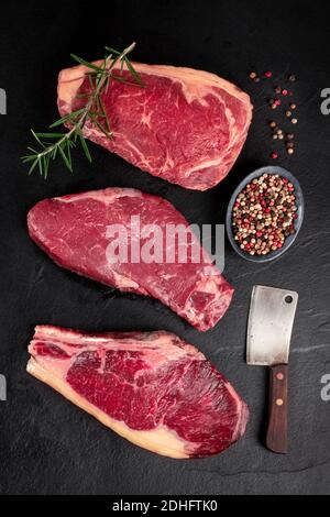 Fleisch, verschiedene Rindersteaks, von oben mit einem Metzgermesser geschossen und gewürzt Stockfoto