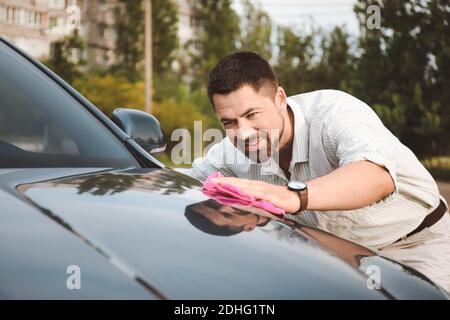 Hübscher Mann, der sein Auto im Freien wäscht Stockfoto