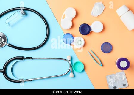 Behälter mit Kontaktlinsen, Lösungen, Stethoskop und Pinzette auf farbigem Hintergrund Stockfoto