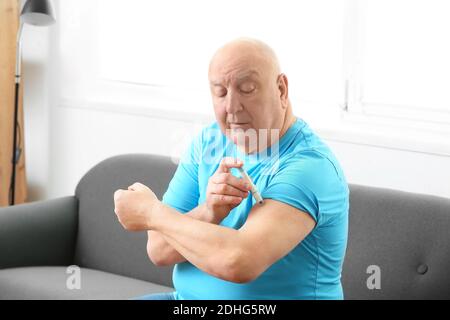 Älterer Diabetiker, der sich zu Hause Insulininspritze gibt Stockfoto