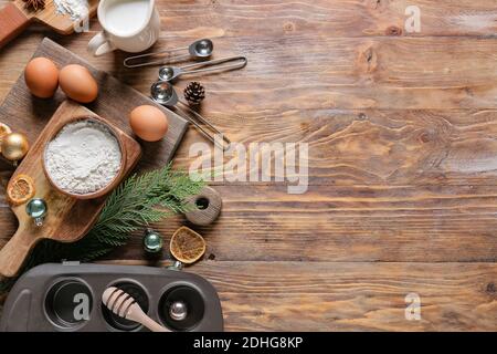 Zutaten für Weihnachts-Muffins und Backutensilien auf Holzhintergrund Stockfoto