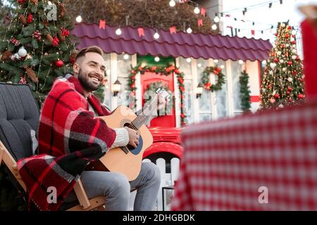 Junger Mann spielt Gitarre im Freien am Heiligabend Stockfoto